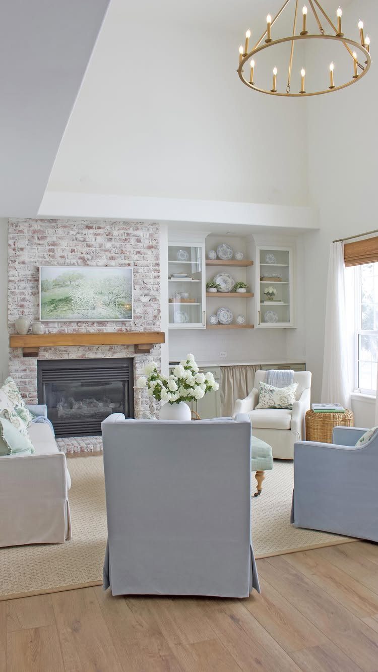 Light blue and white furniture in a bright living room with brick fireplace.