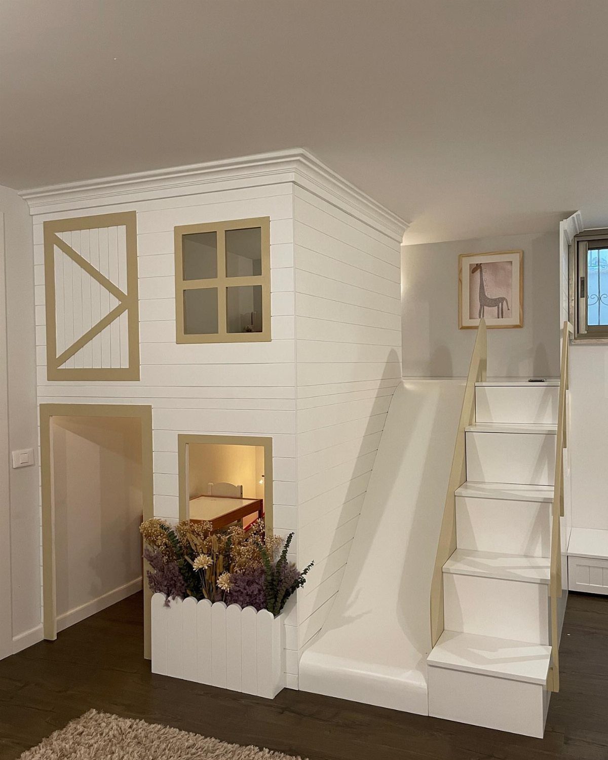 White indoor children's playhouse with a slide, stairs, and small window.