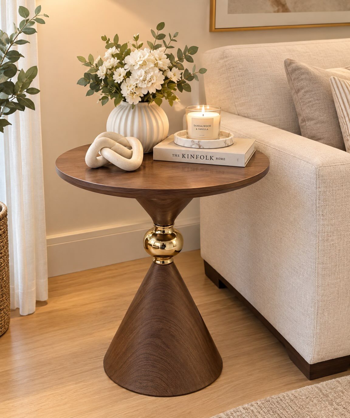 Round wooden side table with gold accent next to a beige sofa