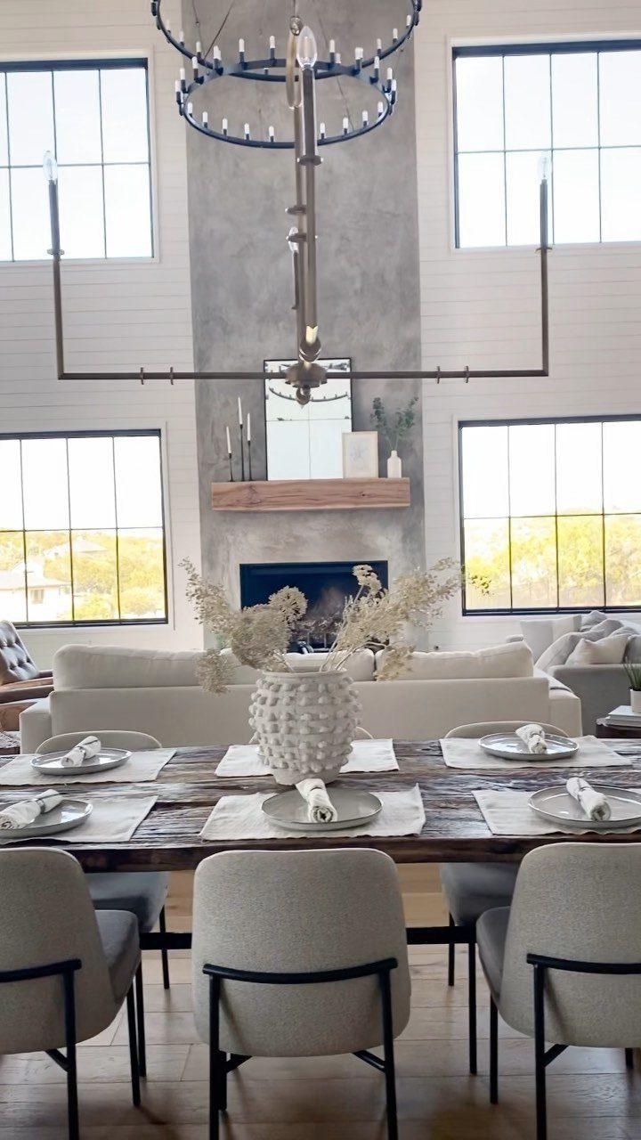 White shiplap walls in a bright living room with a concrete fireplace and chandelier.