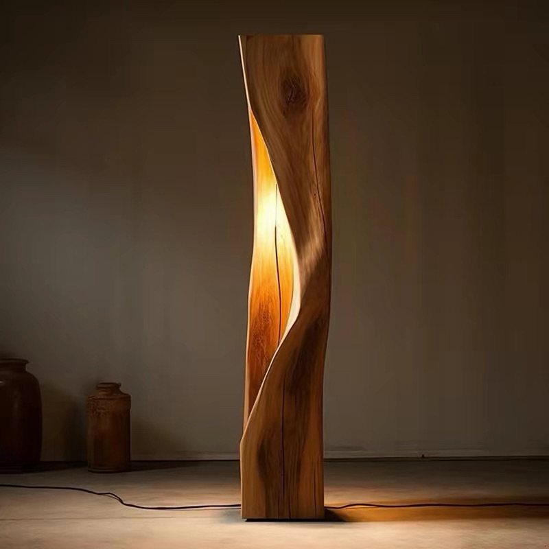 Sculptural wooden floor lamp with warm light glowing from a curved interior slit.
