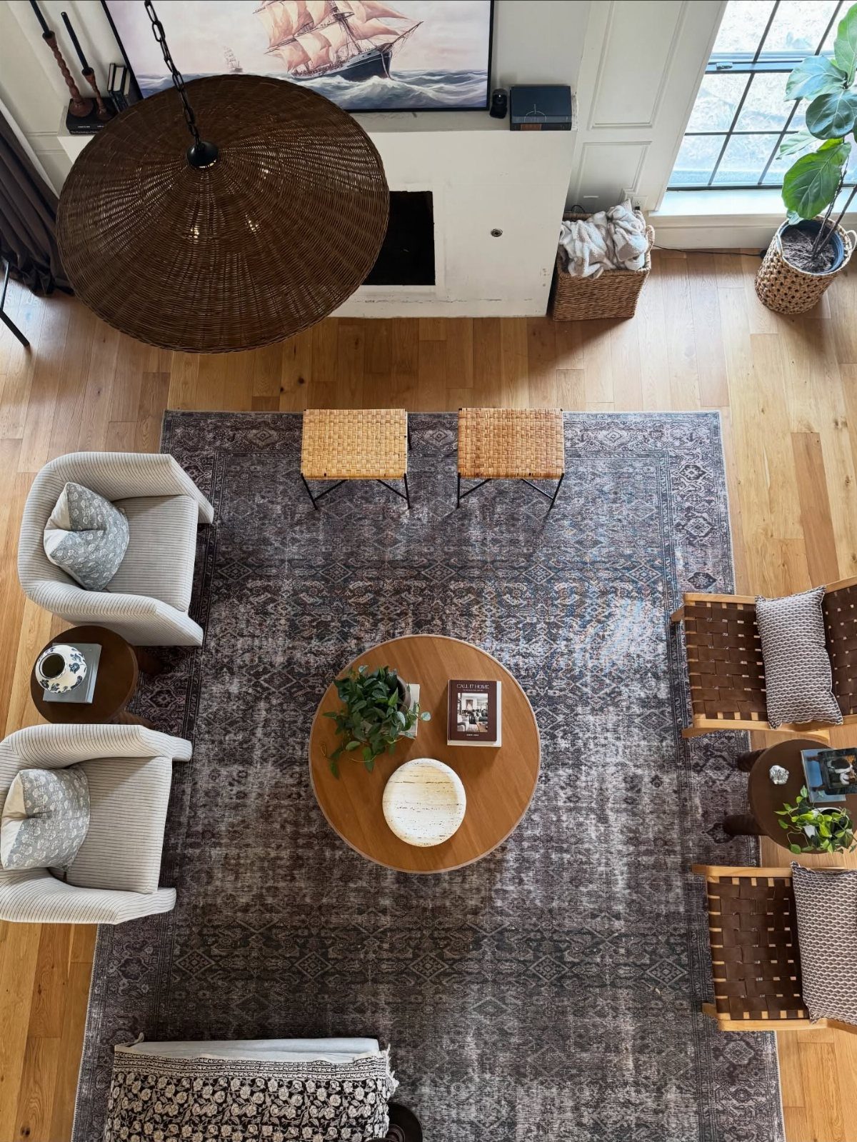 Living room with wooden furniture, grey patterned rug, and large wicker pendant lamp.