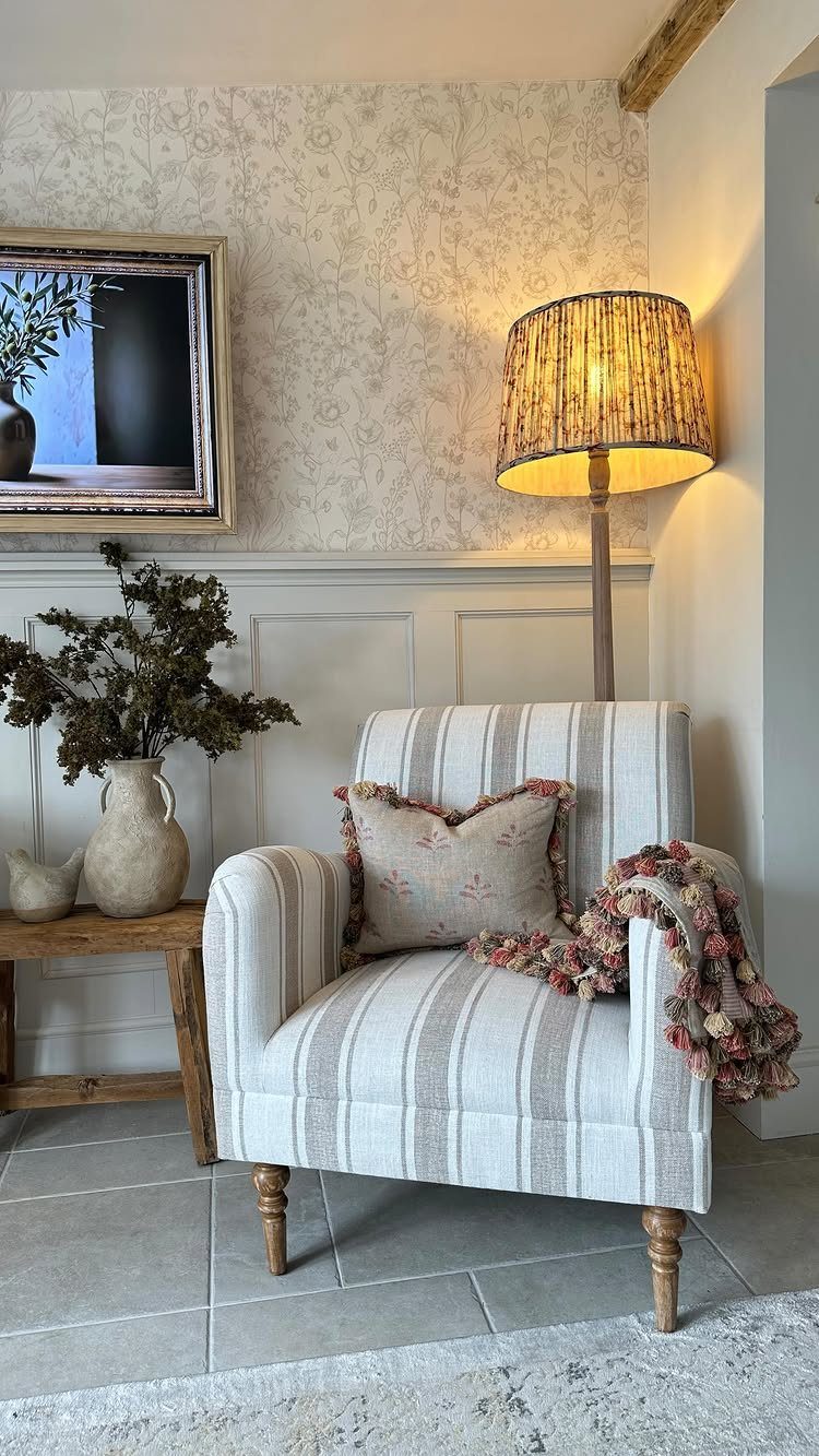 Striped upholstered accent chair with a pillow and throw blanket in a farmhouse room.