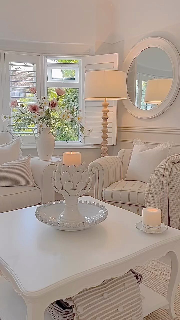 White farmhouse living room with decorative candle holder, striped chairs, and fresh flowers.