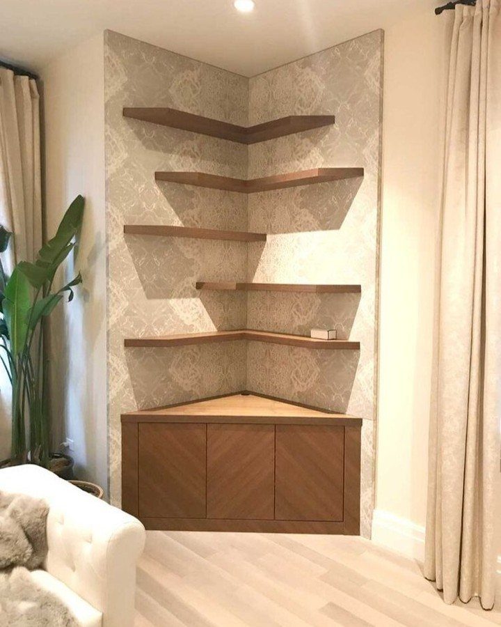 Brown wooden corner floating shelves installed on patterned wallpaper above a corner cabinet.