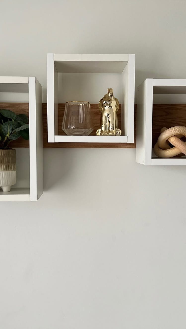 White square floating box shelves on a wall holding small decorative objects