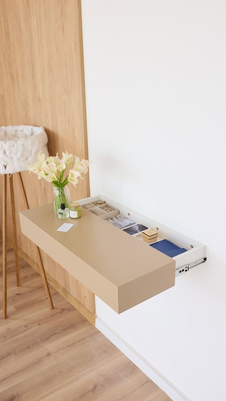 Light wood floating shelf with a pull-out storage compartment and white lilies.