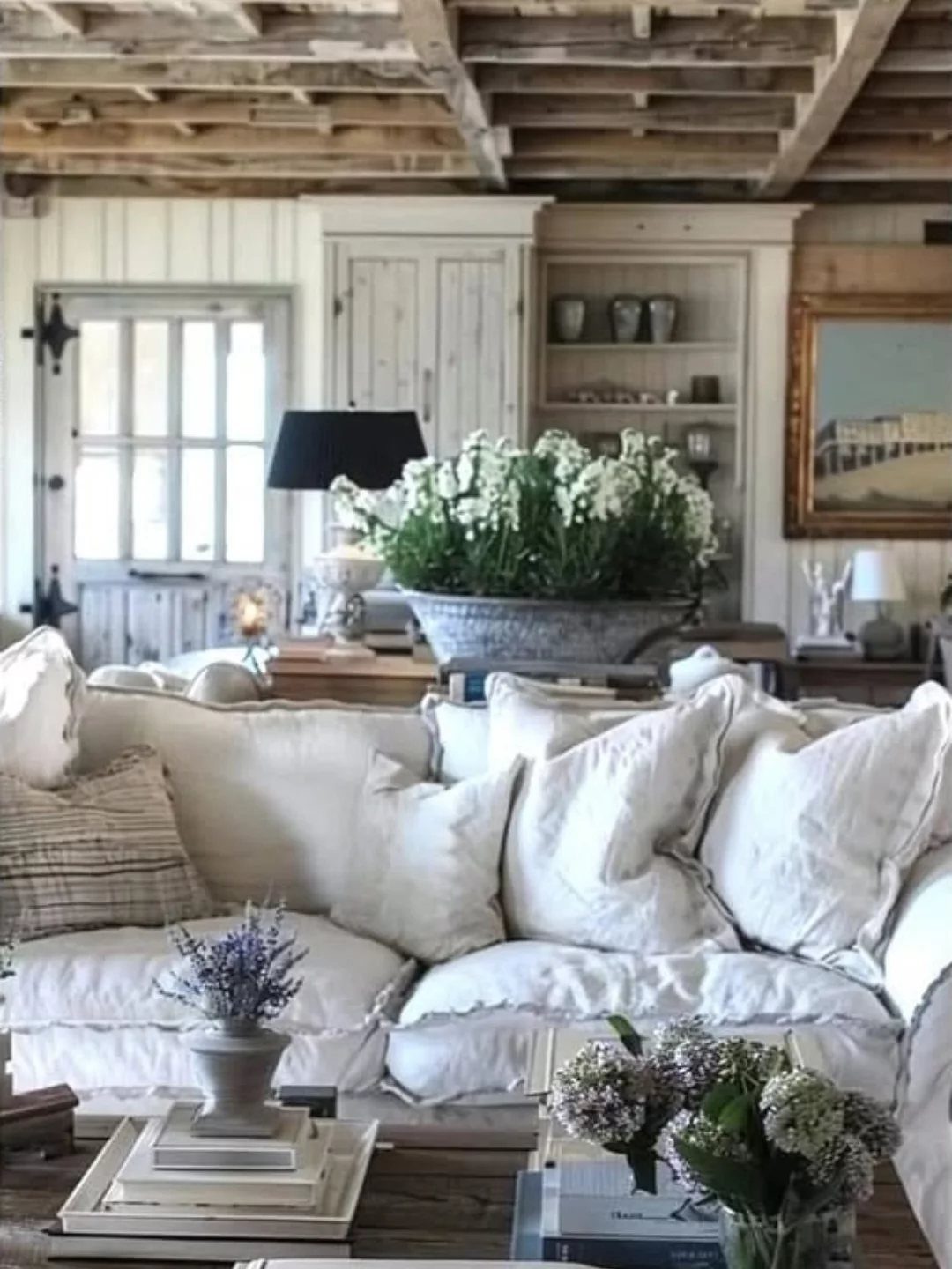White plush sofa in a rustic living room with exposed wooden ceiling beams.