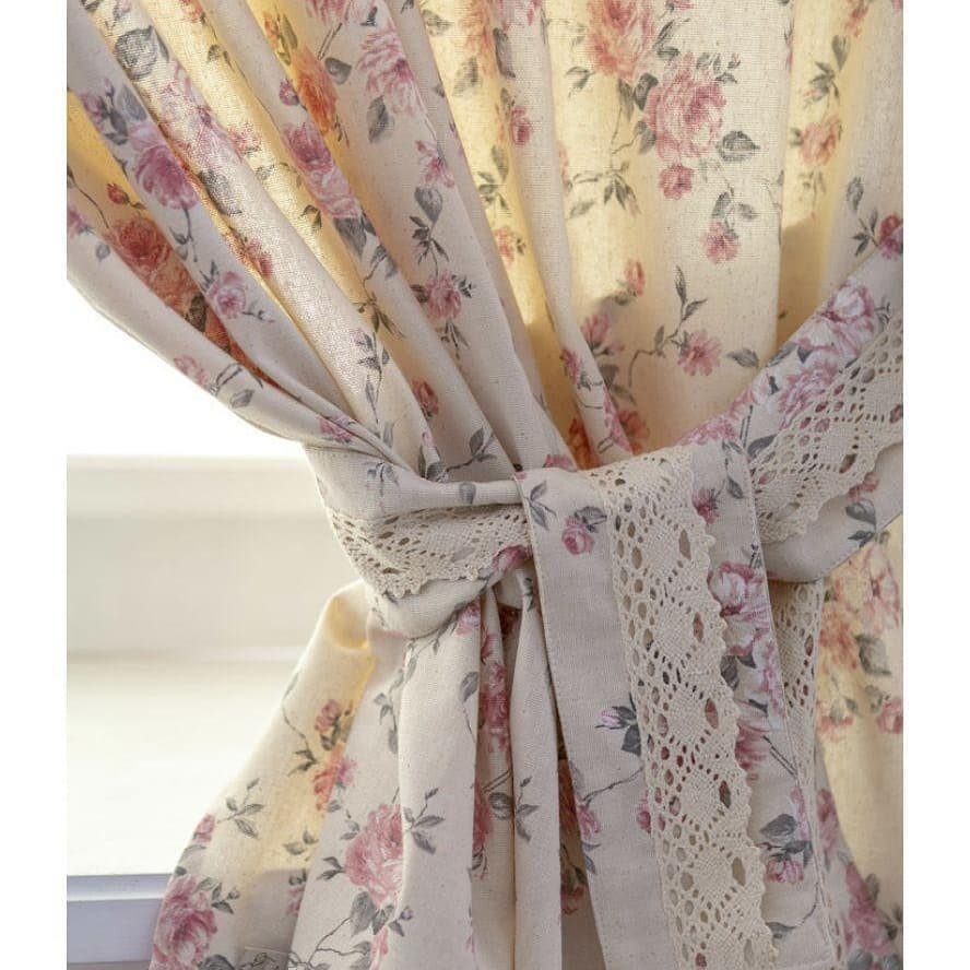 Cream curtains with pink floral rose patterns and a lace-trimmed tie back.