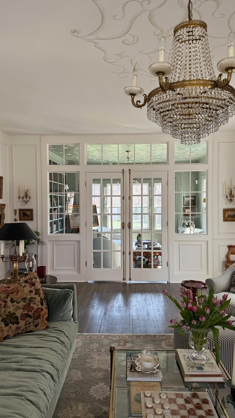 White French doors in a bright living room with a crystal chandelier and sofa.