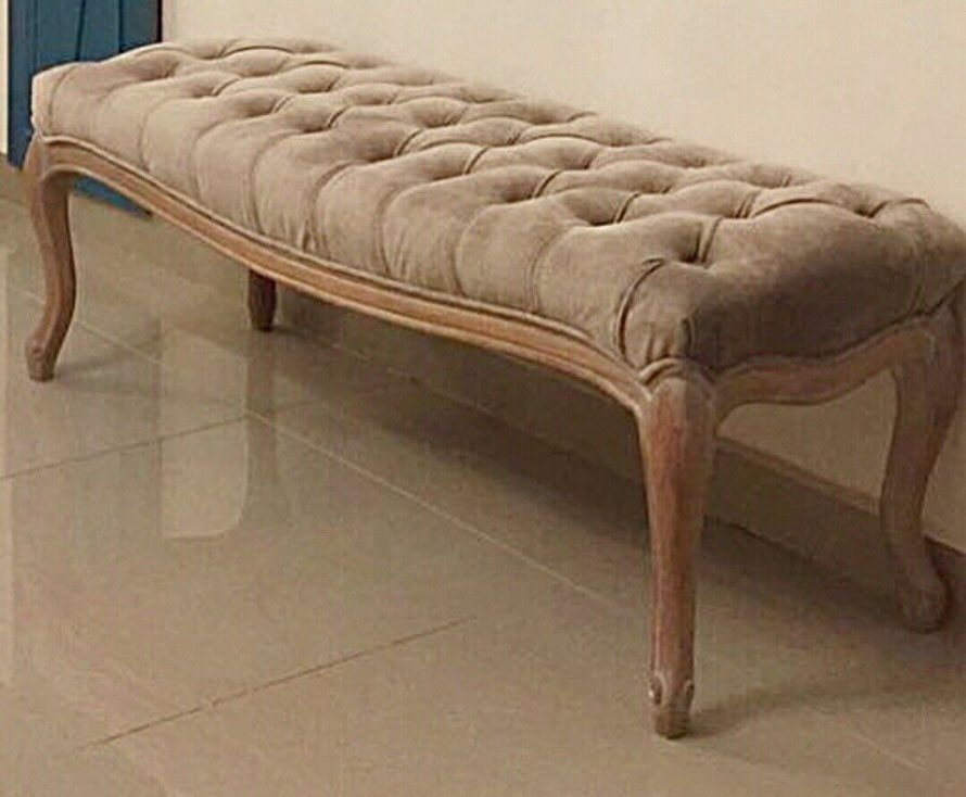 Tufted beige fabric bench with curved wooden legs on a polished tile floor.