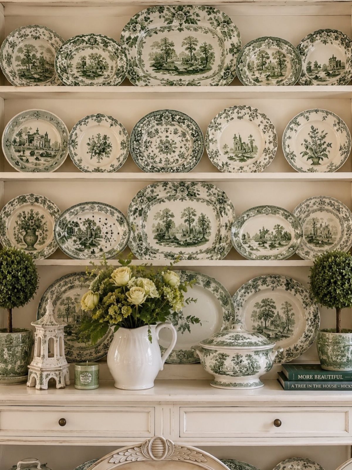 White hutch shelves displaying green and white toile ceramic plates and floral arrangements.