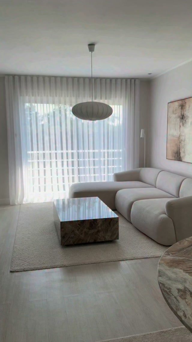 Curved sectional sofa and marble coffee table in a bright, modern living room.