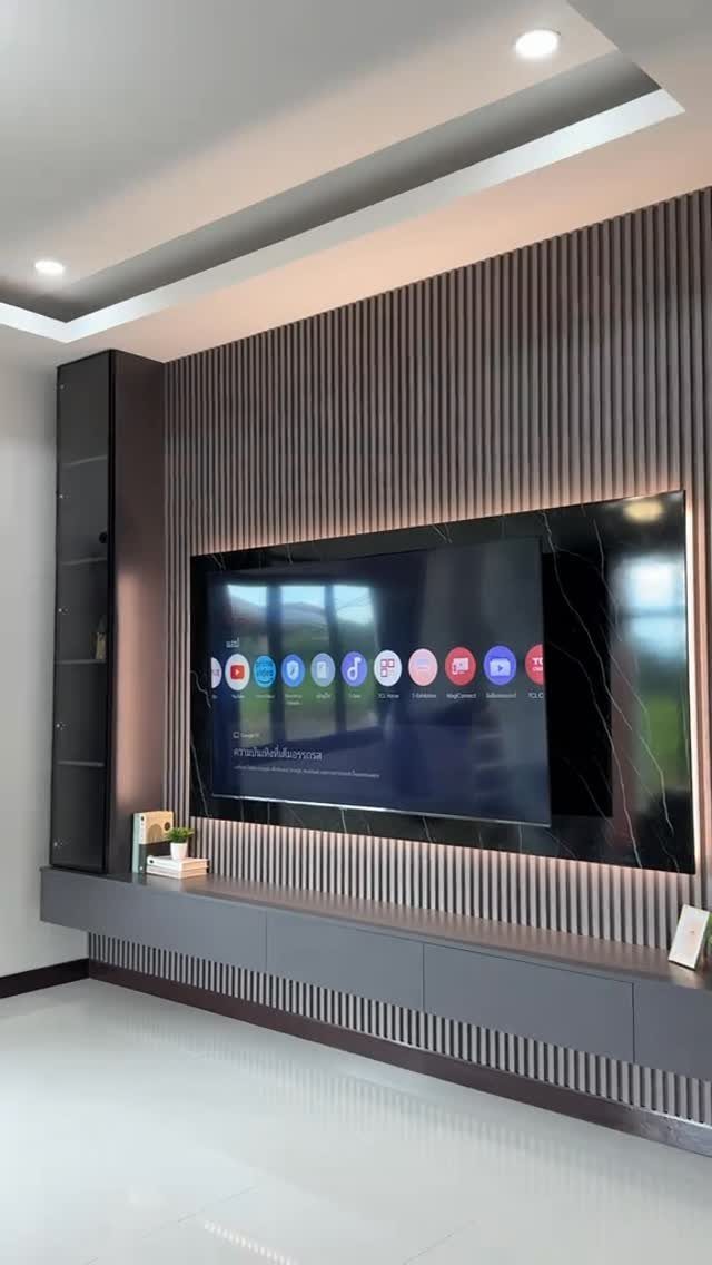 Modern living room with a large TV on a slatted grey wall and floating cabinet.