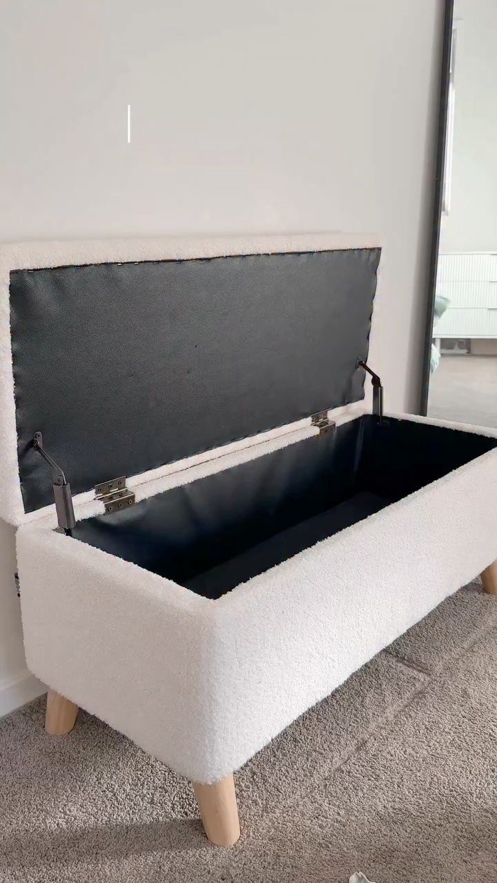 White fabric storage ottoman with open lid revealing a black interior storage compartment.