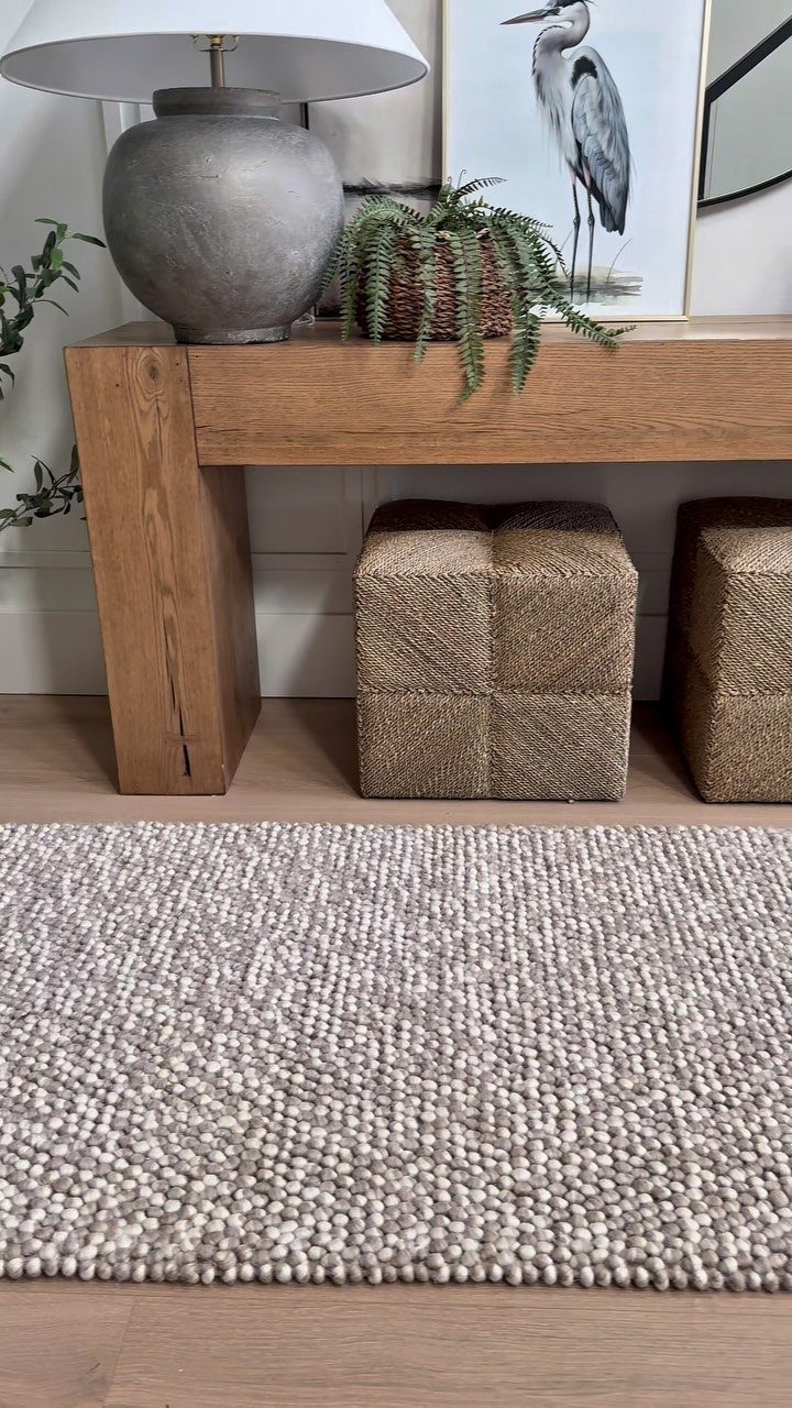Wooden console table with lamp and art above a grey textured area rug