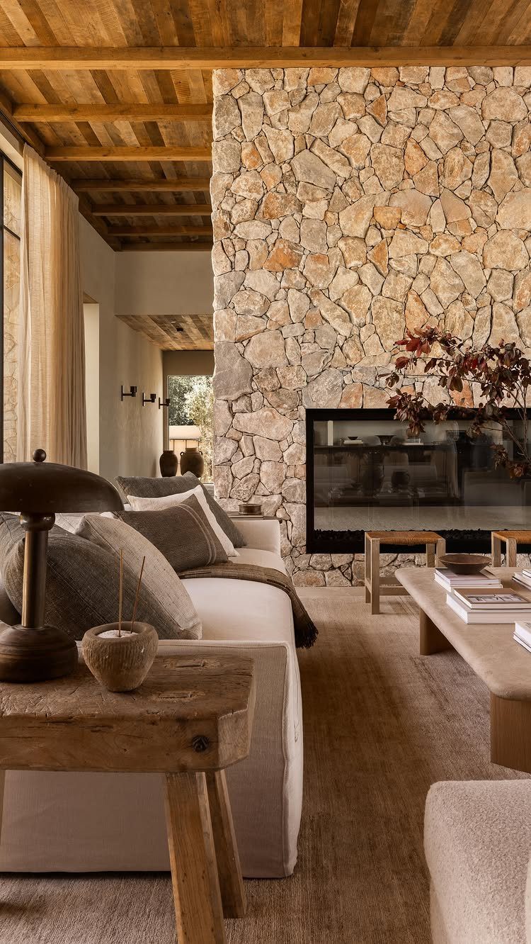 Living room with a stone fireplace, white sofa, and rustic wooden furniture.