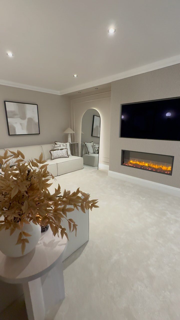 White L-shaped sofa facing a linear electric fireplace with a TV mounted above.