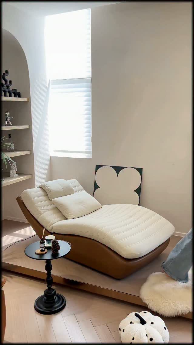 Curved white chaise lounge and black side table in a small white living room