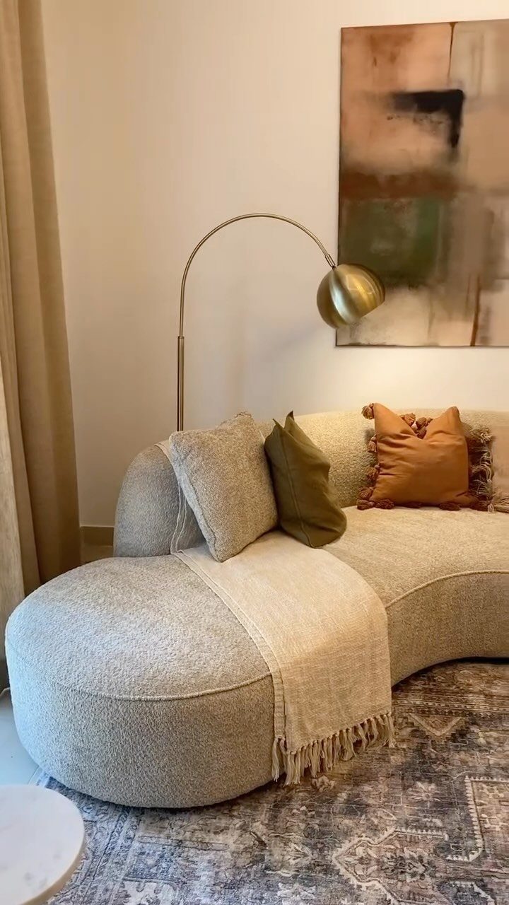 Curved cream bouclé sofa with colorful pillows and gold lamp in a living room