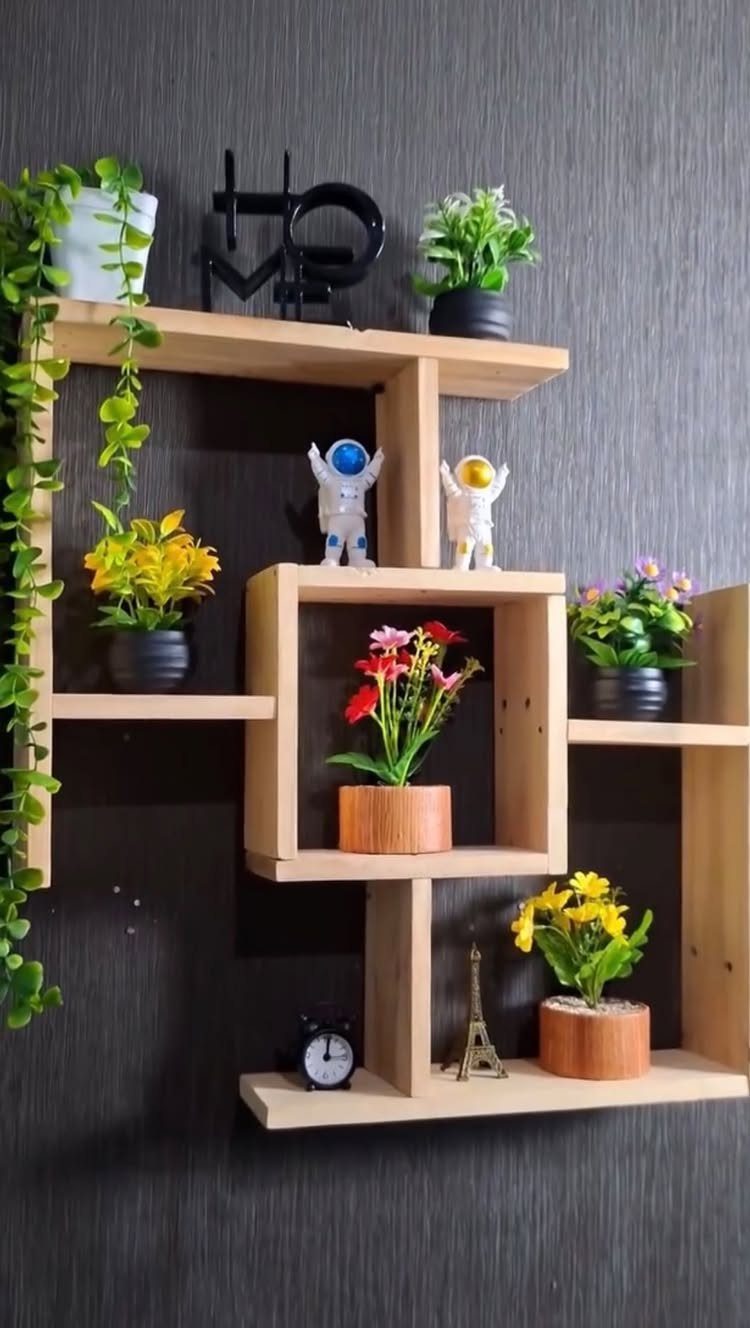 Wooden floating shelves on a dark wall holding small potted plants and miniatures.