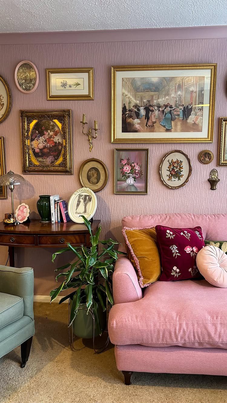 Gallery wall with gold framed art above a pink sofa in a living room