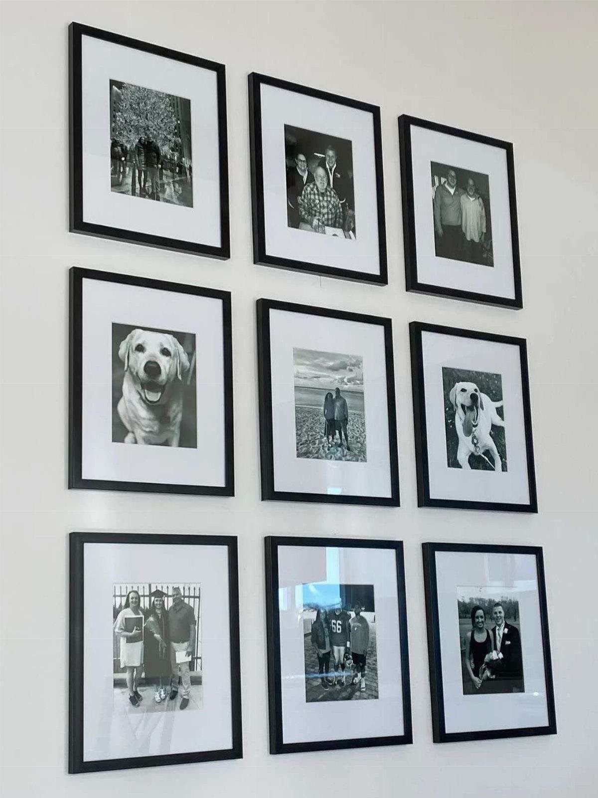Nine black and white photographs in black frames arranged in a grid on a wall
