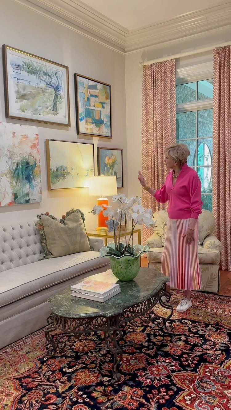 Woman standing in a living room featuring a gallery wall of abstract art.