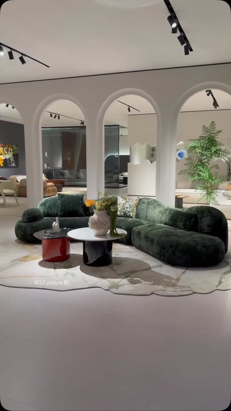 Curved emerald green velvet sectional sofa with modern coffee tables in white room