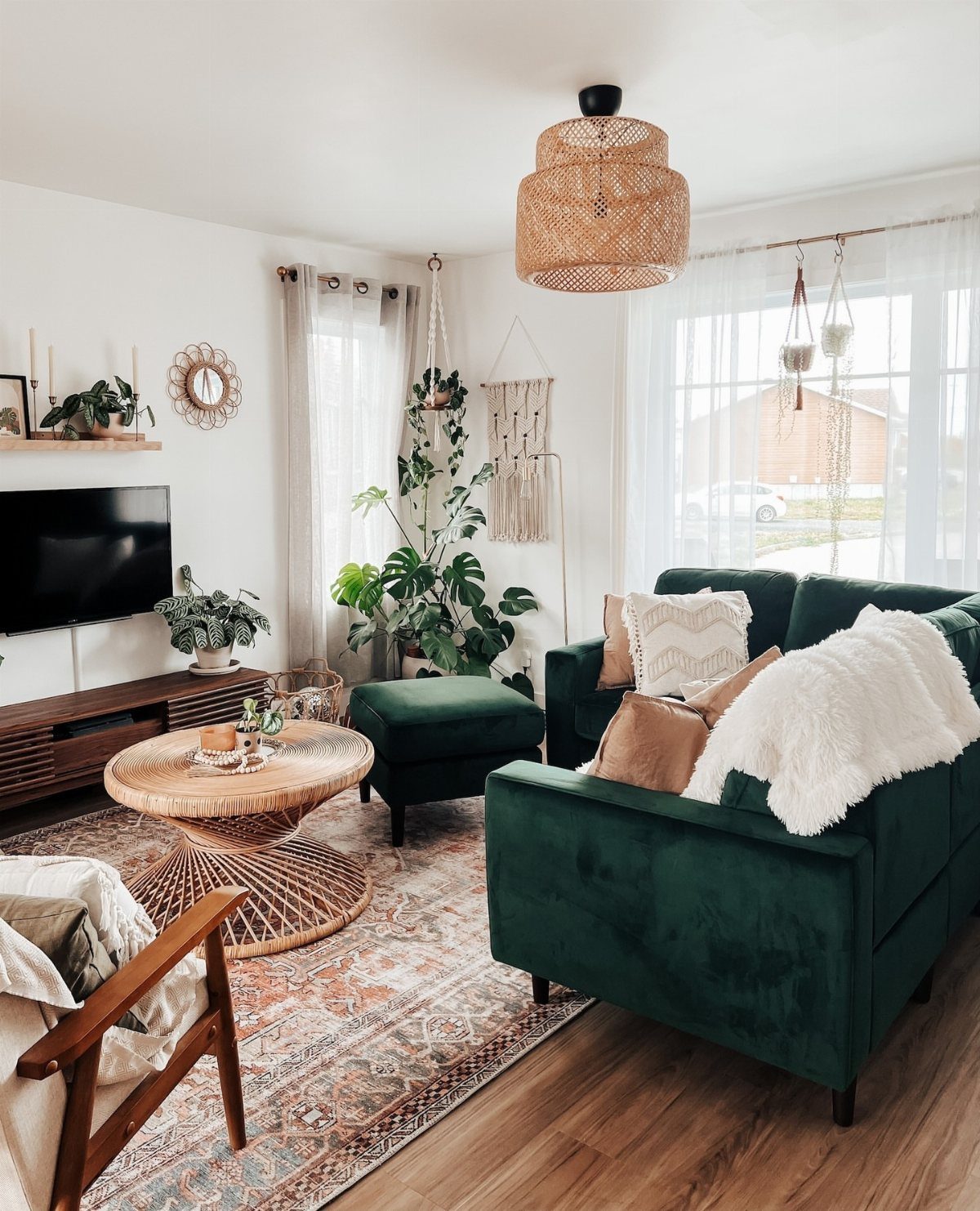 Dark green velvet sofa with white fluffy throw and plants in bright living room