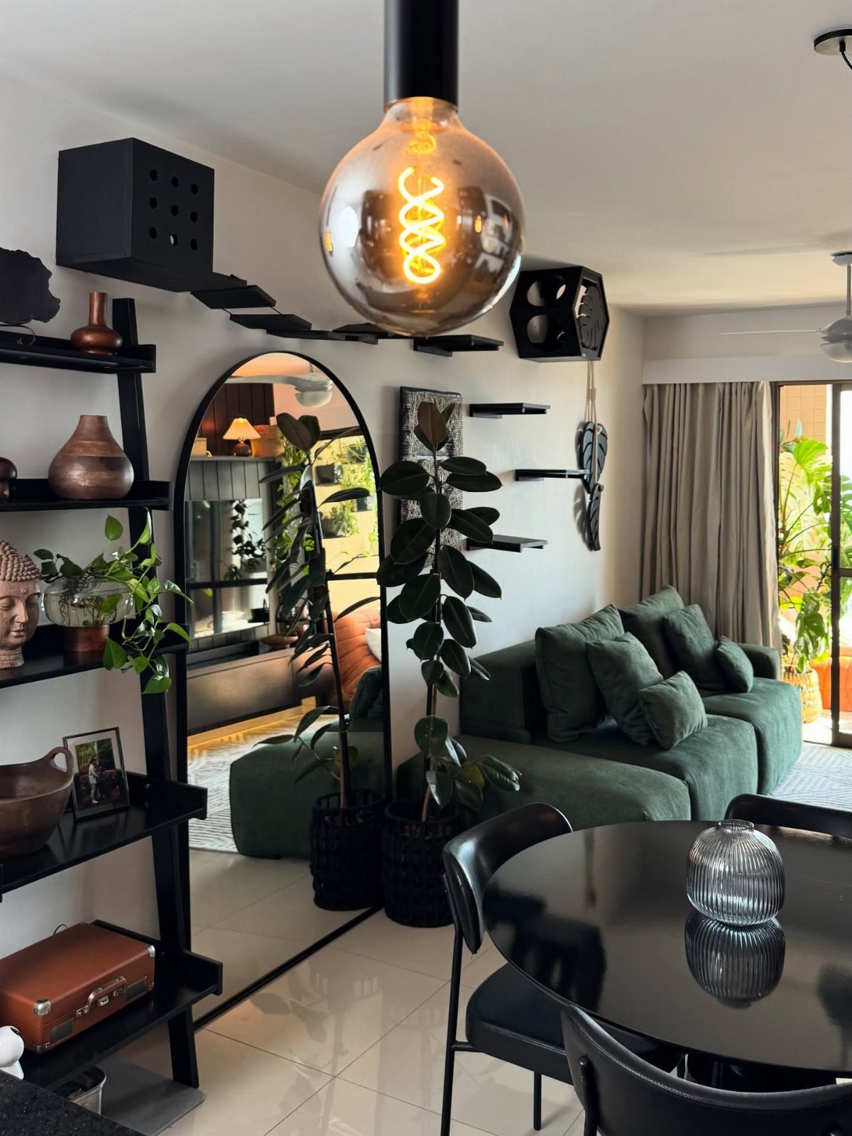 Dark green velvet sofa in a modern room with black furniture and plants.