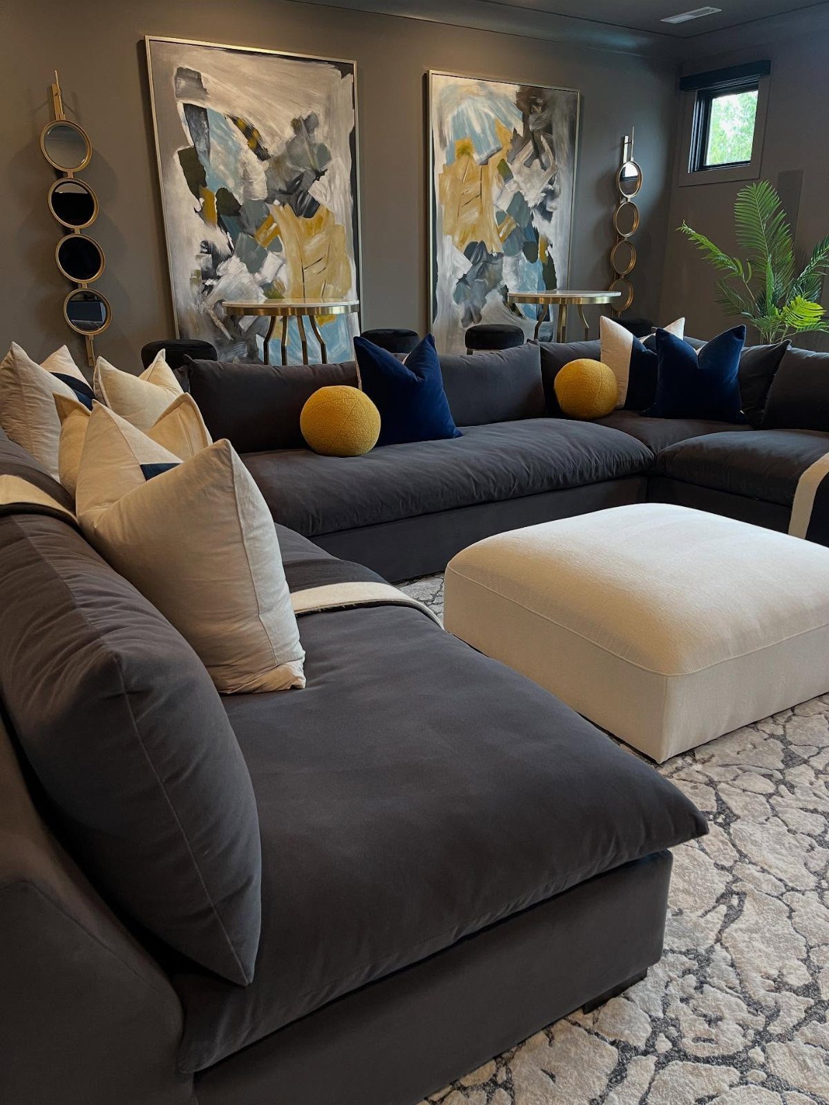 Dark grey sectional sofa in a room with dark grey walls and abstract art.