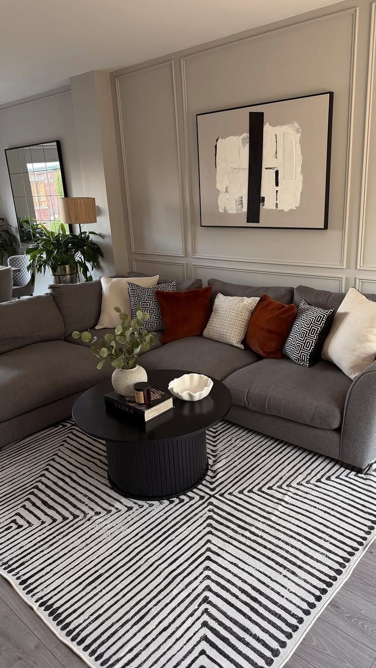 Grey sectional sofa with layered rust and white cushions in a modern living room