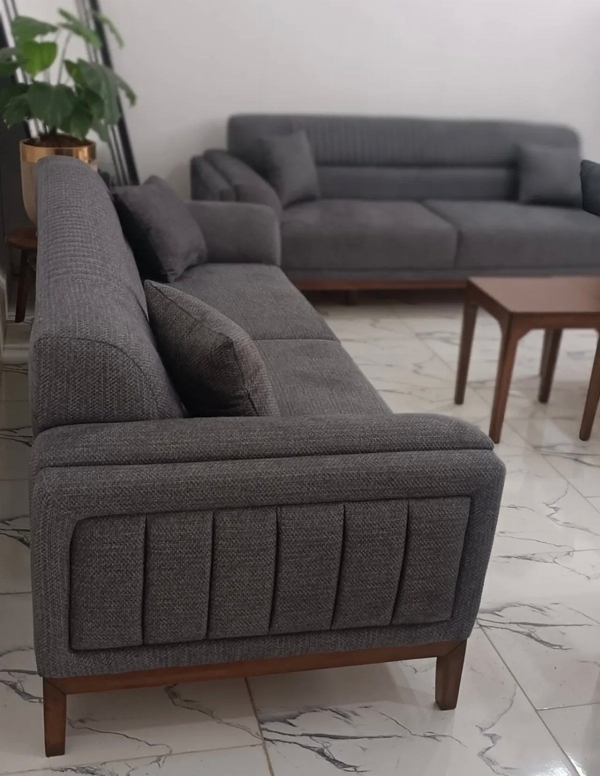 Grey fabric sofas with warm wood legs and a matching wooden coffee table.