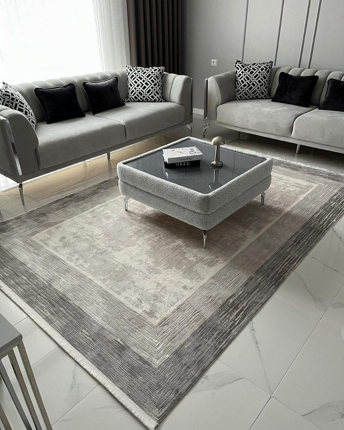 Light grey sofas and a matching coffee table on a grey woven rug.