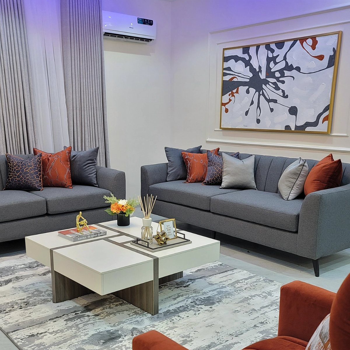 Grey sofas with orange cushions and a white coffee table in a modern living room