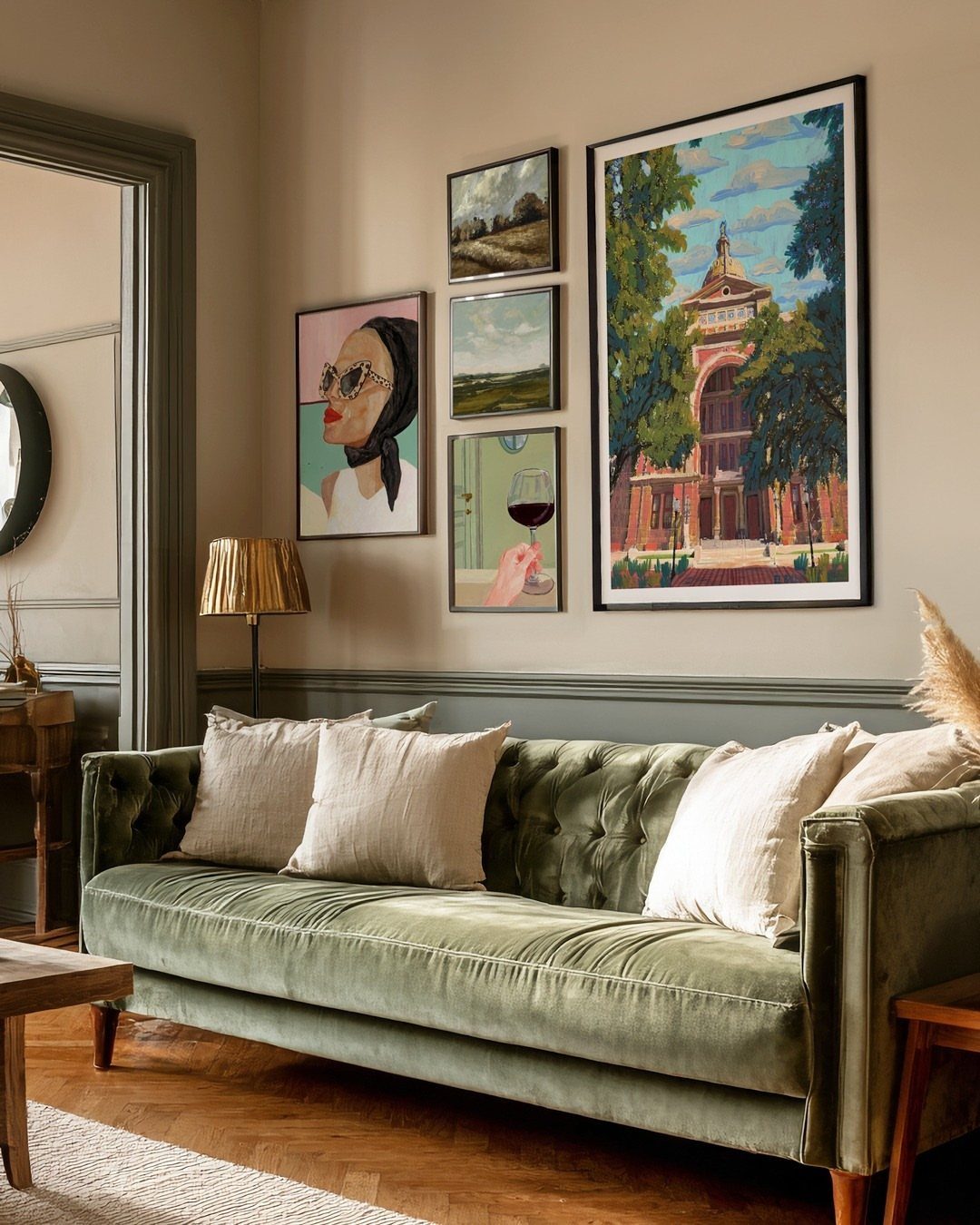 Green velvet sofa with a gallery wall of framed art hanging above it.