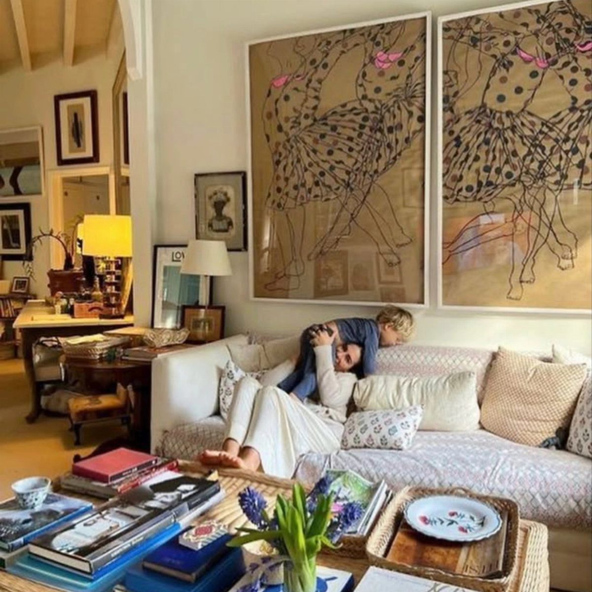 Two large framed dancer paintings hanging on a wall above a white couch.