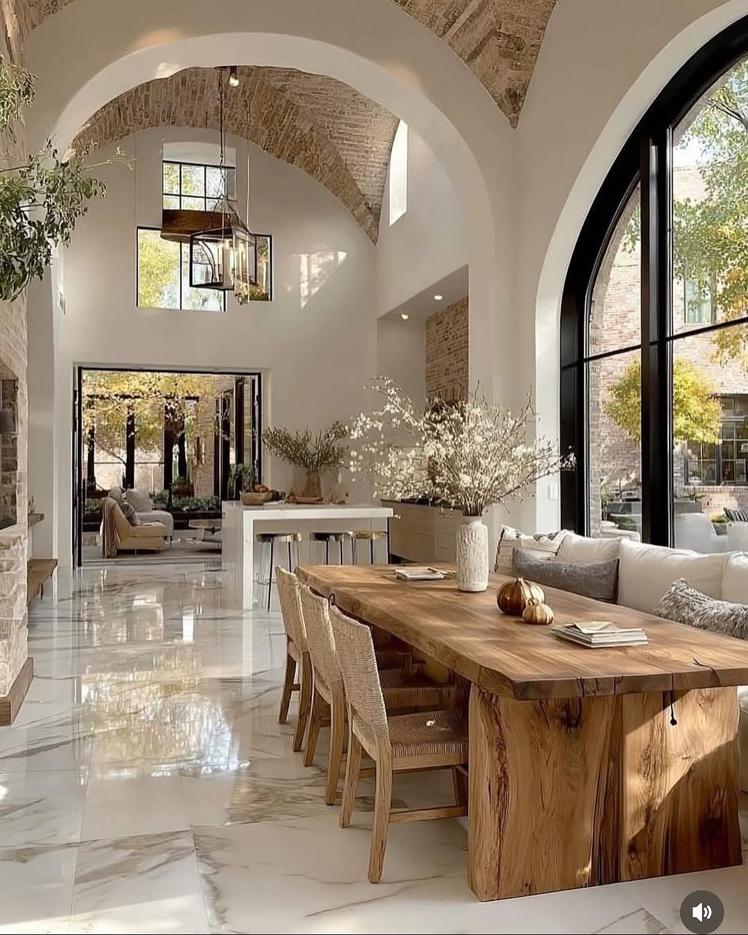 High vaulted ceiling living room with marble floors and a wooden dining table