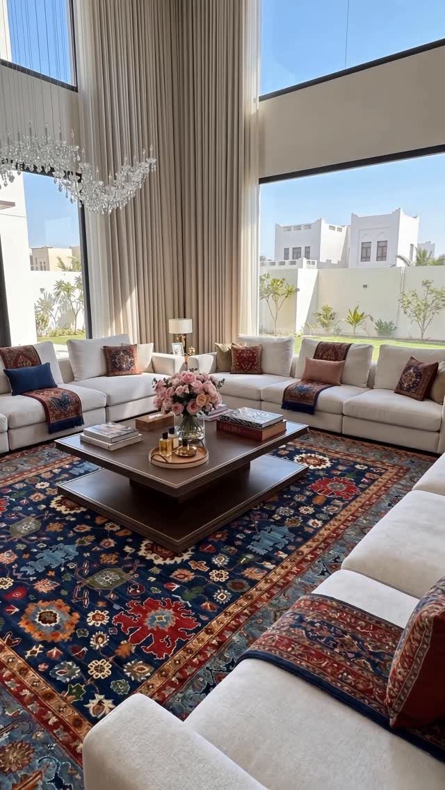 Large ornate blue and red patterned rug grounding a high ceiling living room