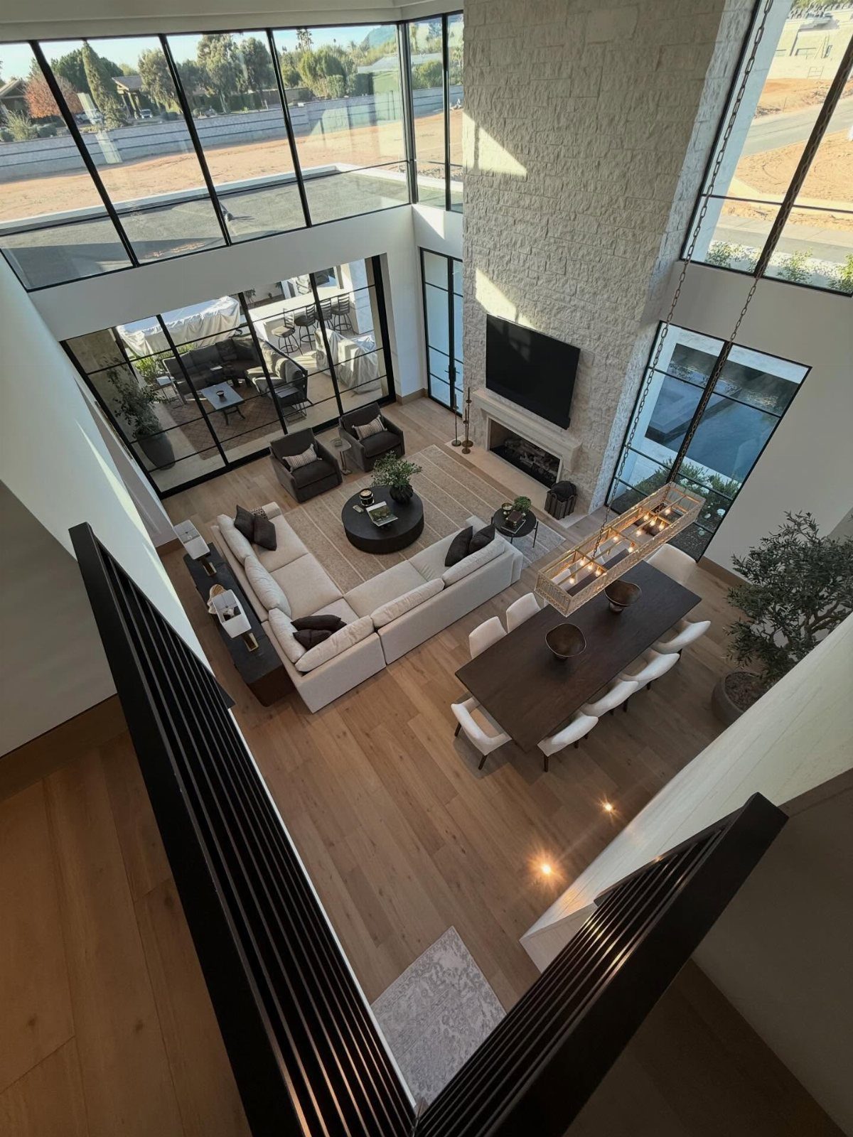 Modern living room with light wood flooring, white sectional, and high ceilings.