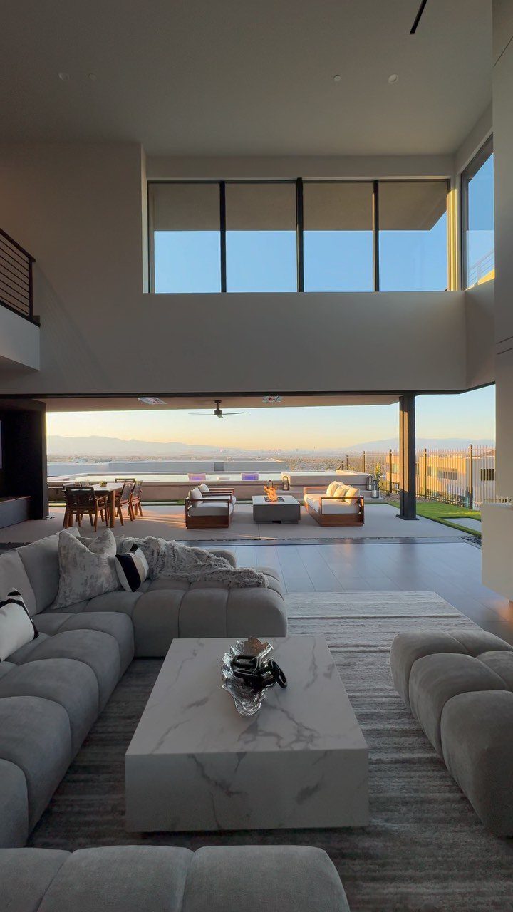 Modern living room with high ceilings, grey sectional, and open view to patio.
