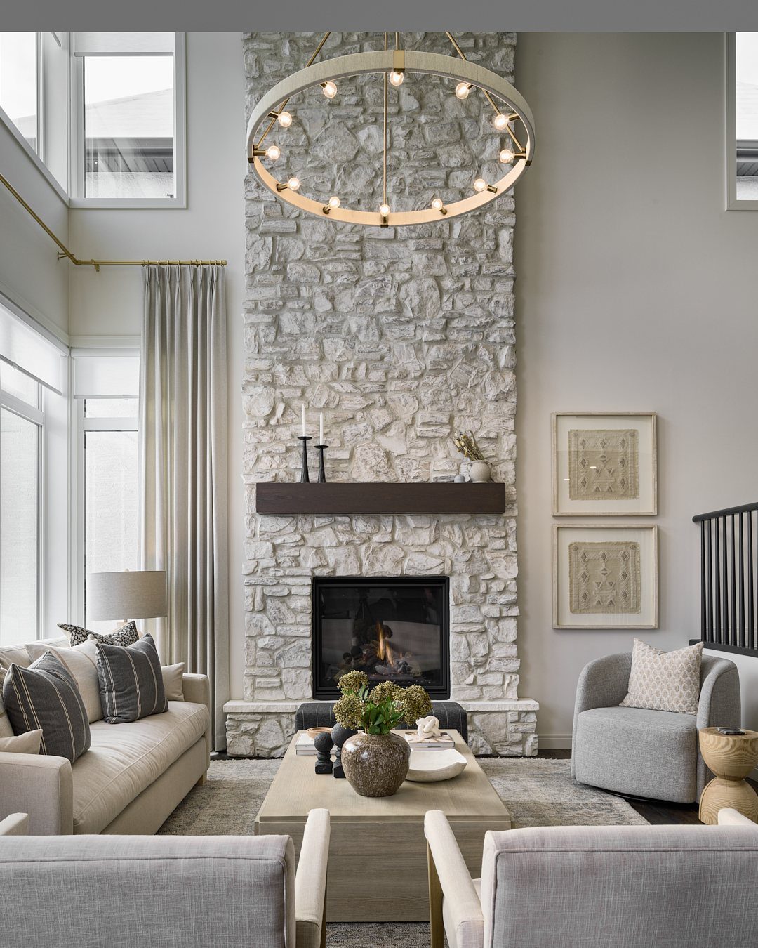 Living room with high ceilings, stone fireplace, and a large circular gold chandelier.