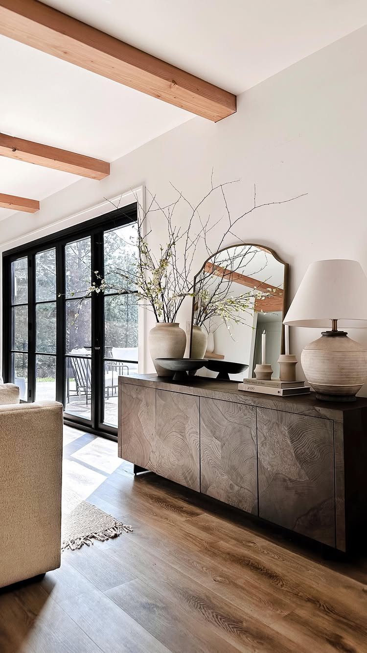 Dark wood console table behind a beige sofa decorated with a mirror and lamp