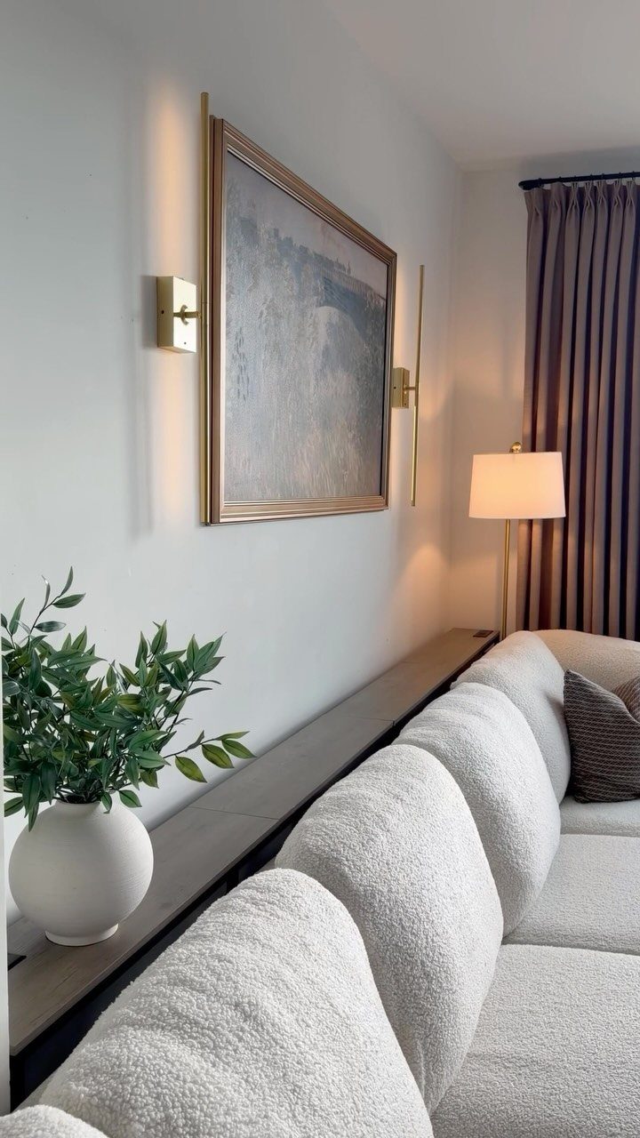 Dark wood console table behind a white sofa with a plant and wall art.