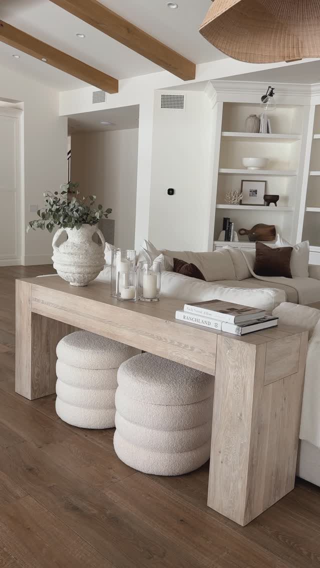 Light wood console table behind a white sofa decorated with a vase and books