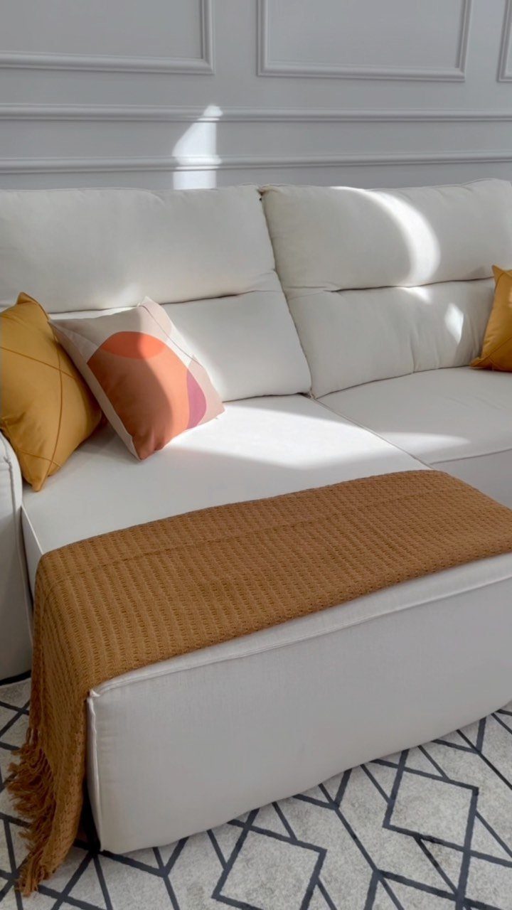 Mustard yellow blanket draped over a white sectional sofa with decorative pillows