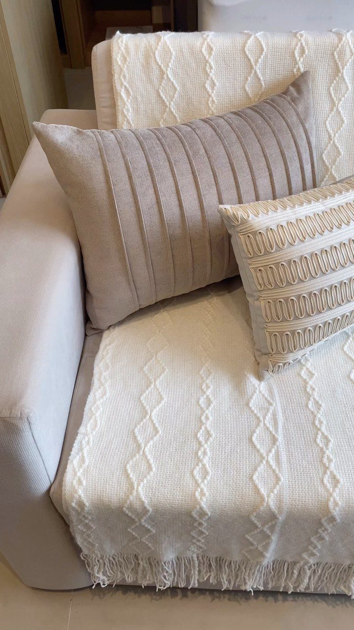 White textured blanket draped over a grey sofa with neutral decorative pillows