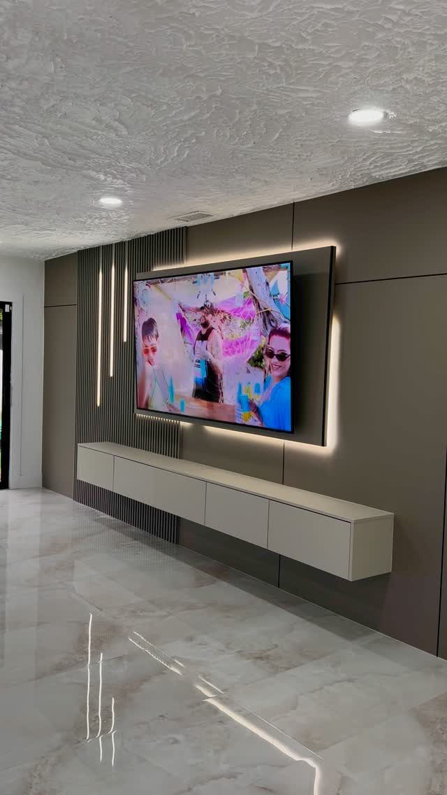 Wall-mounted television with backlighting and a textured accent wall with vertical slats.
