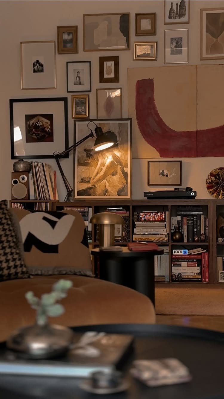 Living room with a dense gallery wall, brown sofa, and filled bookshelves.